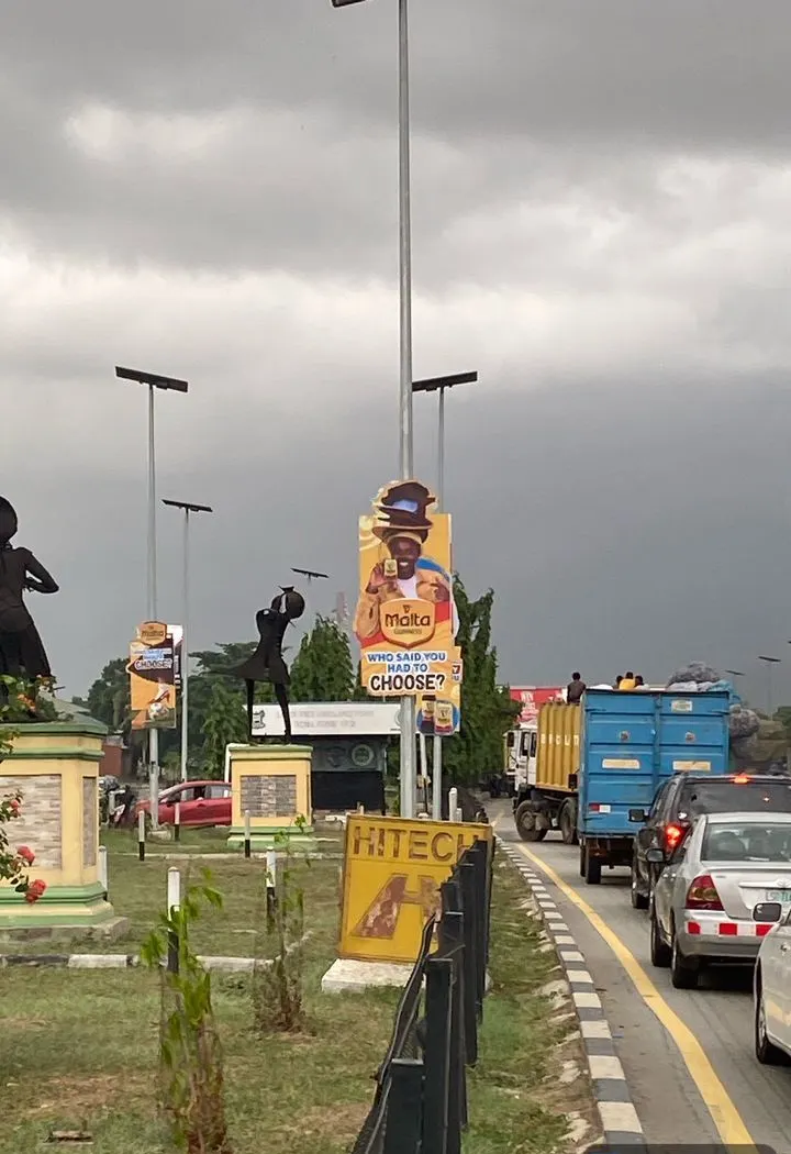 Malta Guinness pole die cut above traffic on the Lagos-Ibadan Expressway, Ikeja