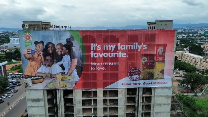 Golden Penny spaghetti wall drape across the top floors of the PDP Building, Abuja, for FMN, seen from a drone