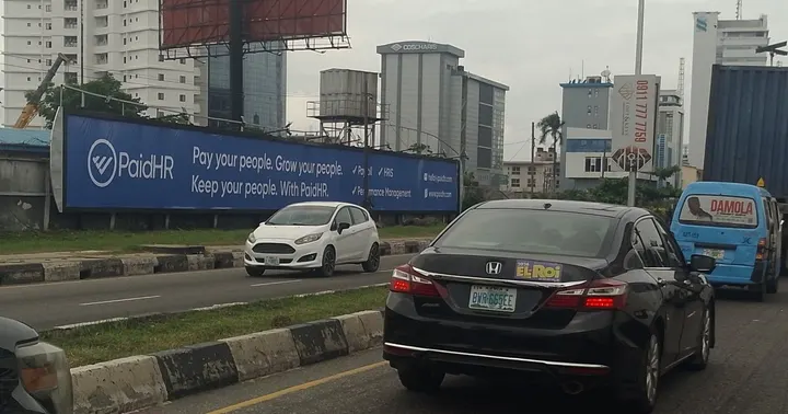 A long run of branded panels on a perimeter fence along Adeola Odeku Street, Victoria Island, Lagos